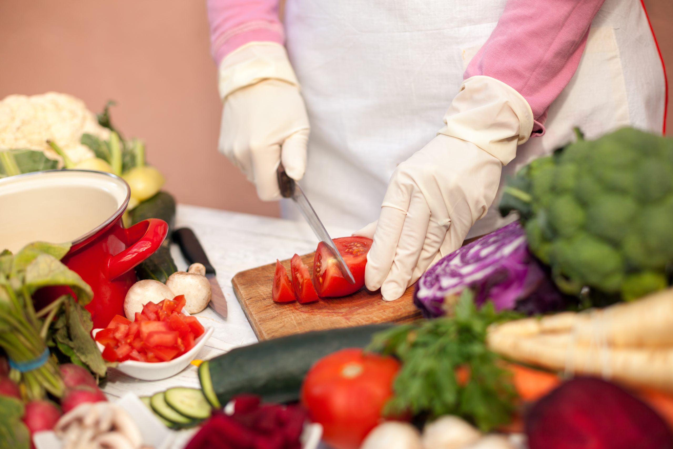 Woman,With,Gloves,Cutting,Tomato,On,Cutting,Board